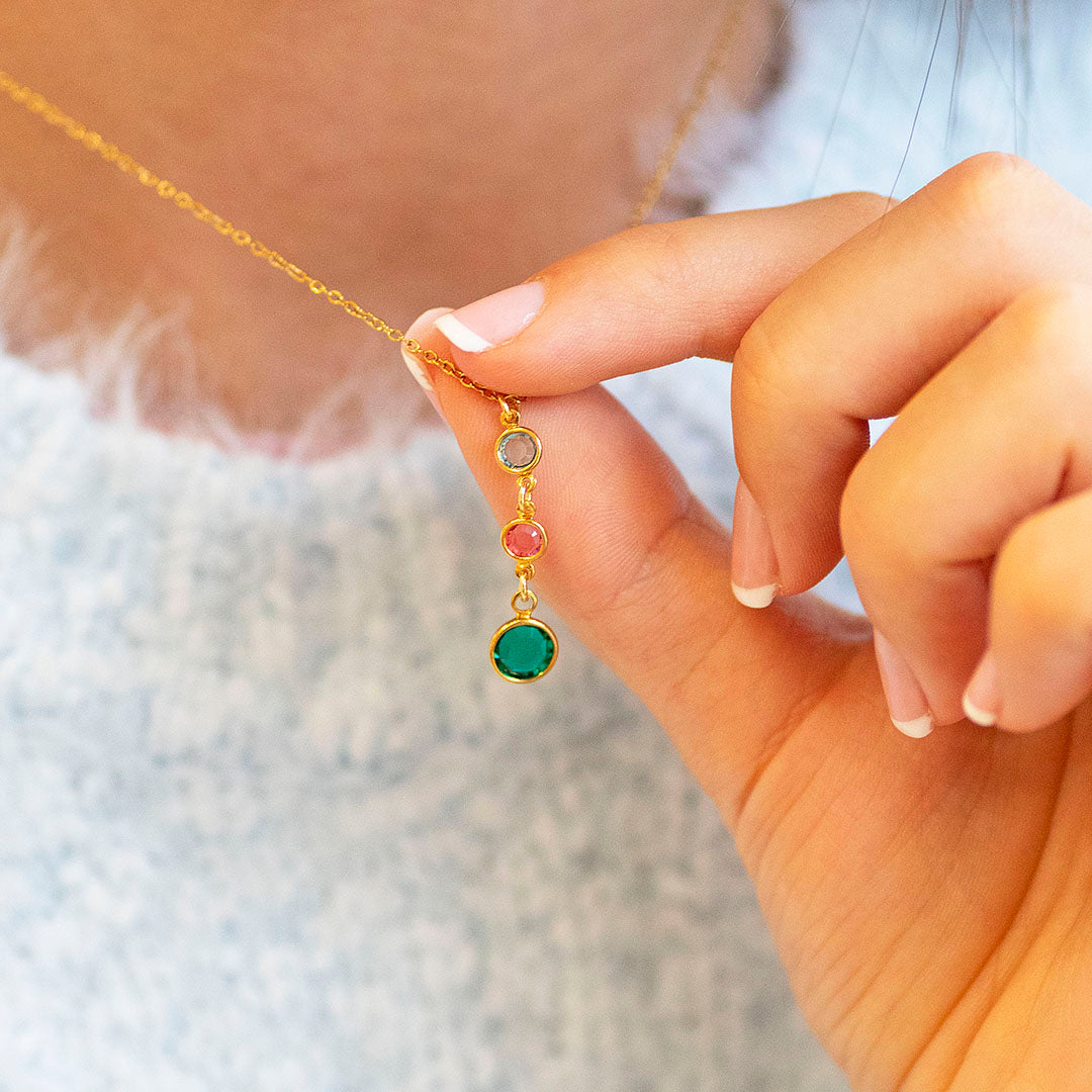 Gold plated Mother and Two Children Birthstone Pendant Necklace with three colourful birthstones, styled with a soft blue jumper.