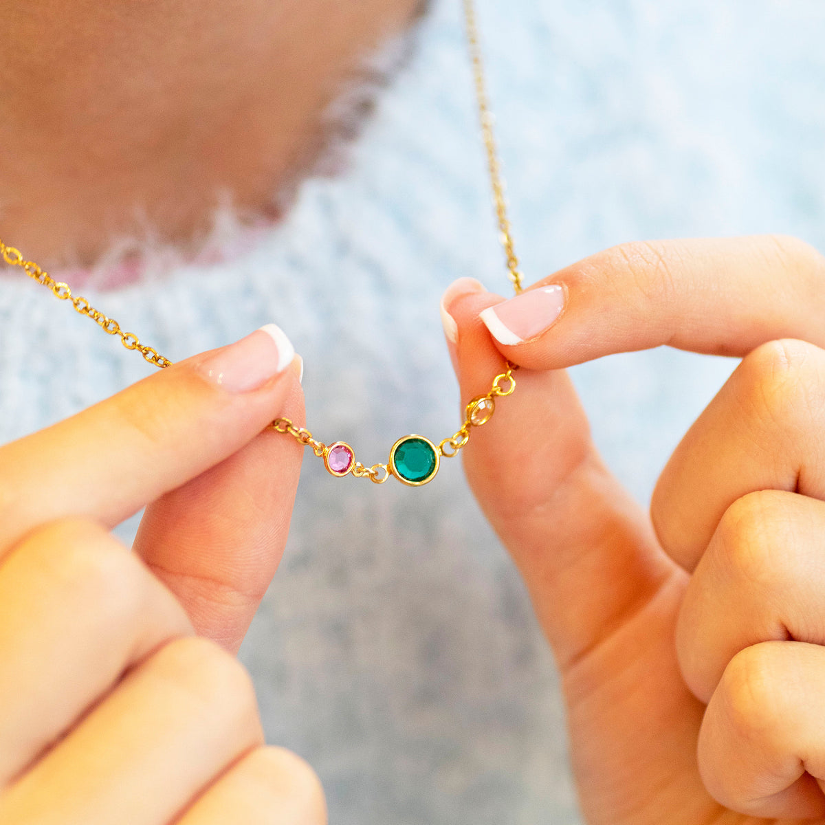 Gold plated Mother and Two Children Birthstone Link Necklace with three colourful birthstones held between the fingers, representing a mother and her two children.