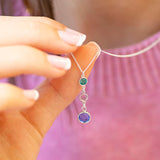 Sterling silver Mother and Two Children Birthstone Pendant Necklace featuring blue, lilac and green birthstones, worn with a pink jumper.