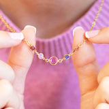 Gold plated Mother and Four Children Birthstone Link Necklace featuring five colourful birthstones on a delicate chain, shown worn with a soft pink jumper.