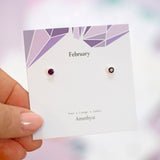 Sterling Silver Minimalist Birthstone Stud Earrings displayed shown in Amethyst on a February birthstone characteristcs card.
