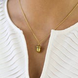 Image shows model wearing gold antique effect acorn pendant necklace