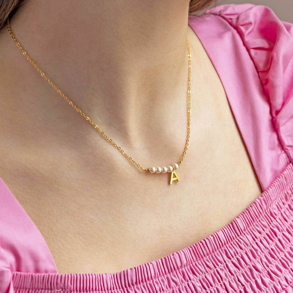 Model wears asymmetric pearl bar initial necklace with the initial A