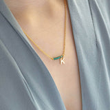 Image shows model wearing asymmetric birthstone bar initial necklace with May birthstone and K initial