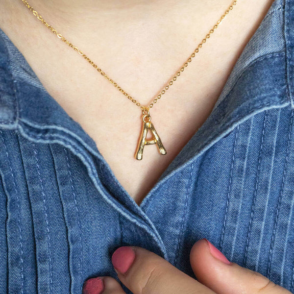 Image shows model wearing bamboo style gold plated initial necklace