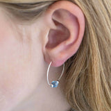 Image shows model wearing silver beaded birthstone hoop earrings with March birthstone