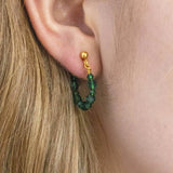 Image shows model wearing Beaded Birthstone Huggie Earrings with May birthstone