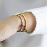 Image shows model wearing rose gold and gold beaded charm bracelet with family birthstones