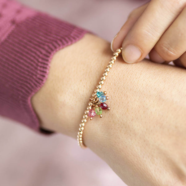 Image shows model wearing beaded charm bracelet with family birthstones
