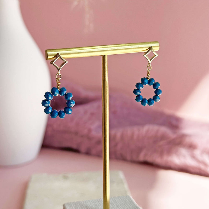 Image shows Beaded Indigo Circle Drop Earrings on a gold earring stand