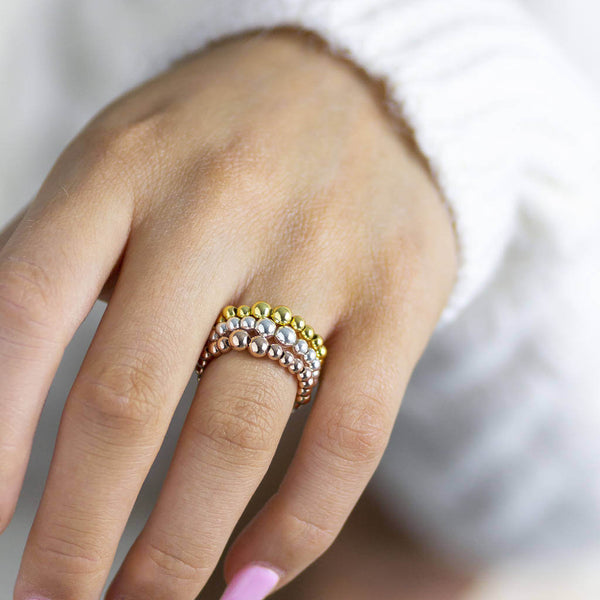 Image shows model wearing gold, silver and rose gold Beaded Stacking Stretch Rings