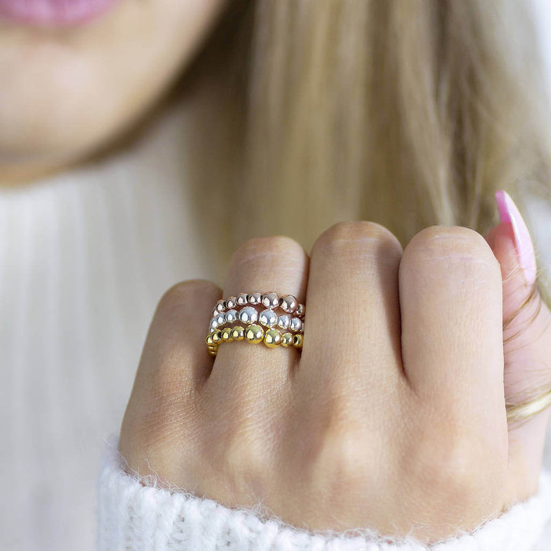Image shows model wearing gold, silver and rose gold Beaded Stacking Stretch Rings