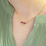 Image shows model wearing birthstone bar necklace with initial charm S and July birthstone