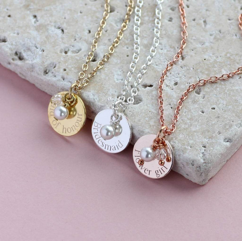 Silver,rose gold and gold bridesmaid pearl and crystal disc charm necklaces lying on a stone square 