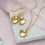 Gold calla Lilly pearl jewellery set with white pearl sitting  a stone square coaster