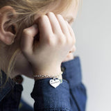 Image shows model wearing Childs personalised sister charm bracelet with little sister and November birthstone