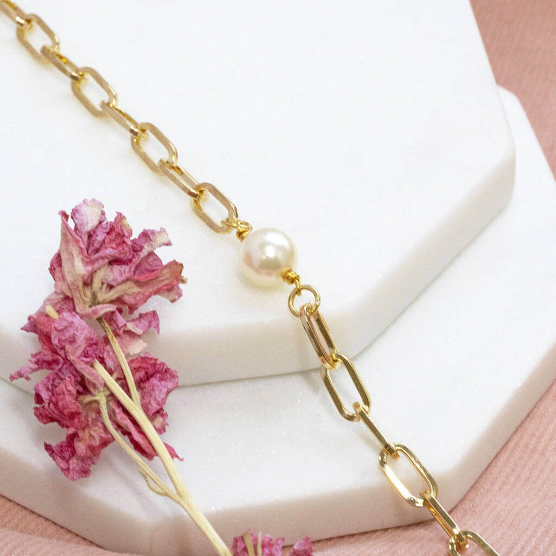 Chunky chain pearl bracelet lying on white hexagon coasters with pink dried flower and on pink material