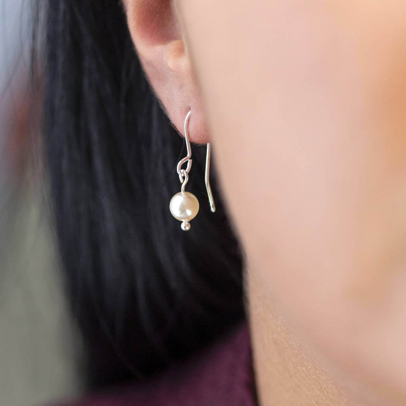 Model wears classic pearl  drop earring in silver with classic ivory