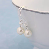 Classic silver pearl drop earring with ivory pearl hanging for a white bowl with silver rim