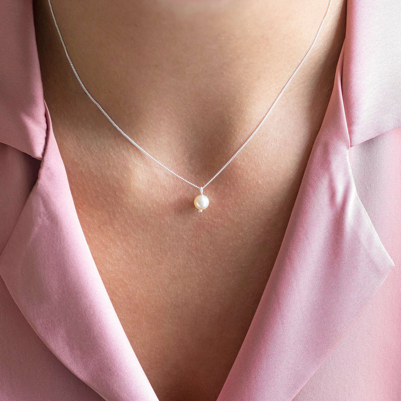 Model wears classic pear drop pendant necklace in silver with an ivory pearl