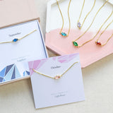 Images shows a selection of gold plated navette birthstone necklaces,two necklaces are om birthstone charictaristics card 