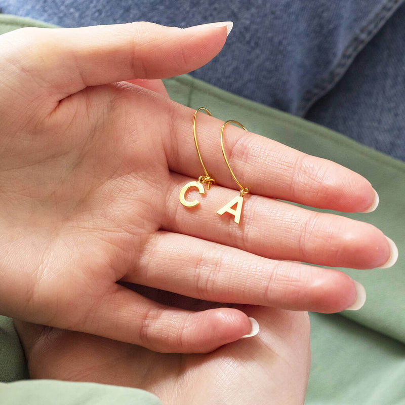 Image shows model holding Dainty Initial Charm Hoop Earrings with initials C and A