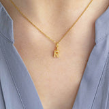 Model wears gold dainty pearl initial necklace with the initial R