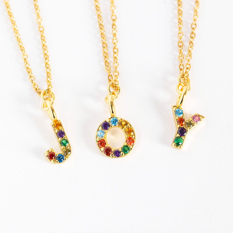 Image shows three gold dainty rainbow alphabet initial necklaces spelling J O Y 