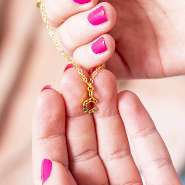 Image shows model holding dainty rainbow initial charm bracelet with Initial C