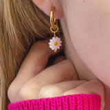 Image shows model wearing daisy charm Huggie hoop earring