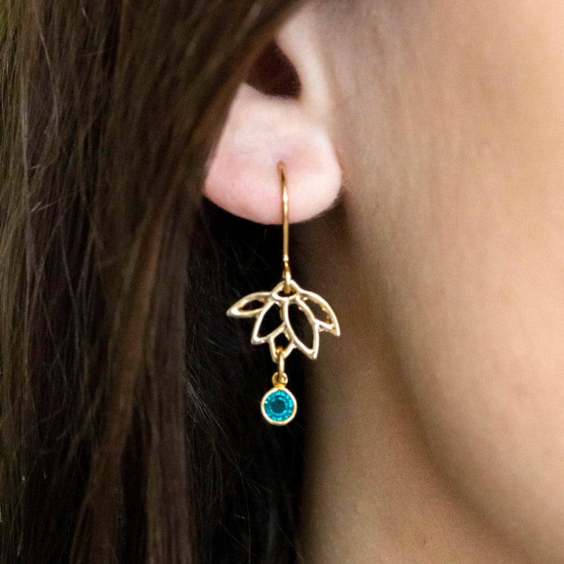Image shows model wearing Delicate Lotus Birthstone Earrings with December birthstone