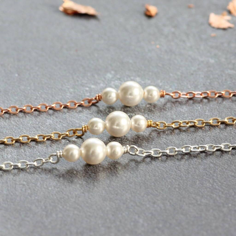 Delicate pearl trio bracelet in rose gold ,Gold and silver on grey counter