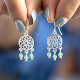 Image shows model holding silver Dreamcatcher Birthstone Charm Earrings with August birthstone