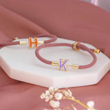 Image shows 2 Enamel Initial Cord Bracelets with K and H initial