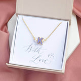 Enamel initial necklace with pearl details and K initial in a gift box on a with love sentiment card sitting a white hexagon coaster