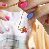 Model holds enamel initial necklace with pearl details and A initial