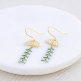 Image shows Enamel Leaf Chain Drop Earrings lying on a white round coaster