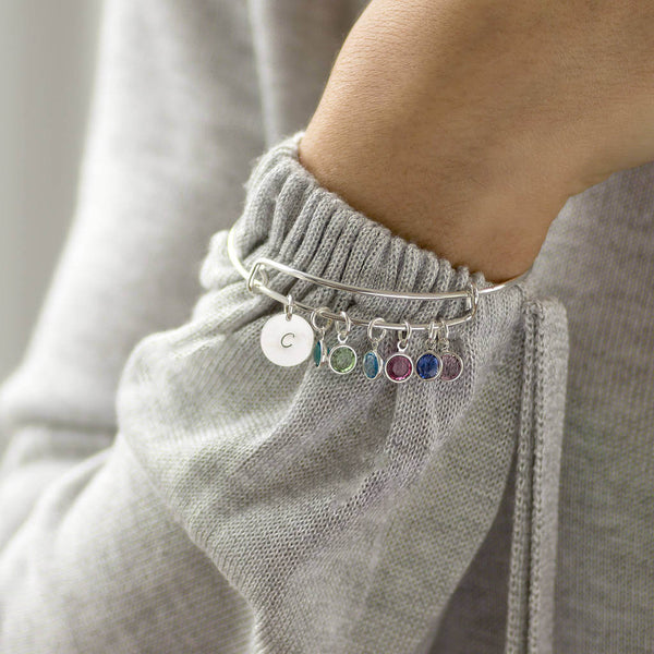 Image shows model wearing family birthstone bangle  with initial C disc and Peridot, Aquamarine, Rose, Saphire and light amethyst 