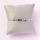 Image shows  family birthstone bar bracelet  on a jewellery pillow