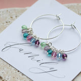 Image shows family birthstone hoop earrings lying on a family sentiment card