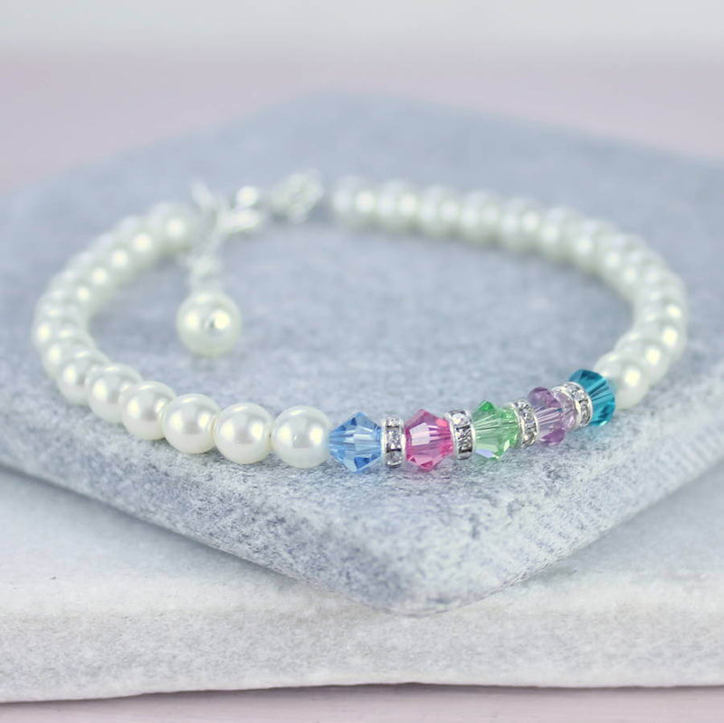 Family birthstone pearl bracelet lying on grey stone coaster