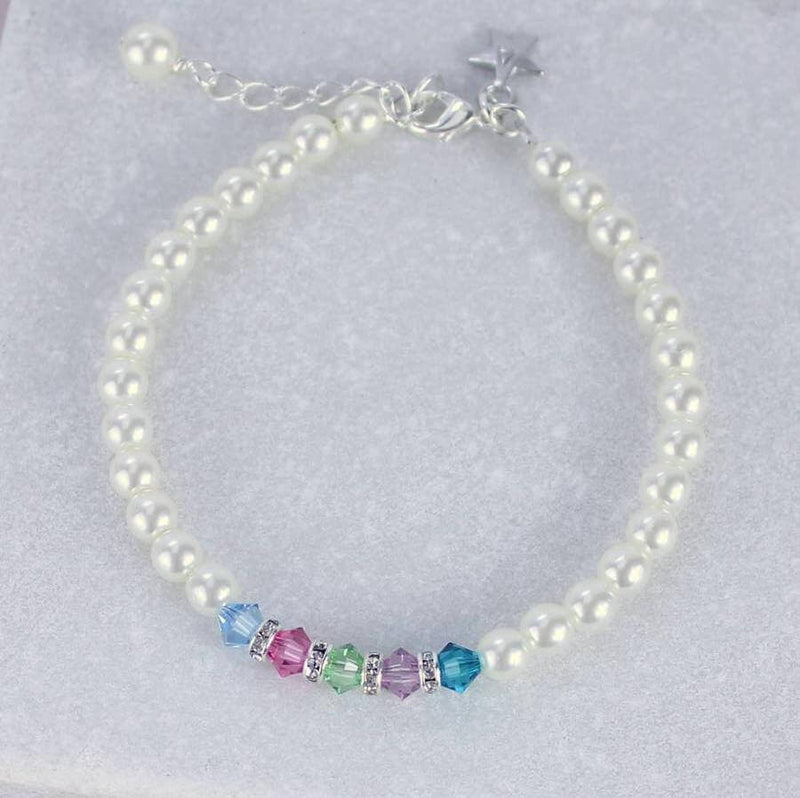 Family birthstone pearl bracelet lying on grey background with a star initial charm ant the clasp