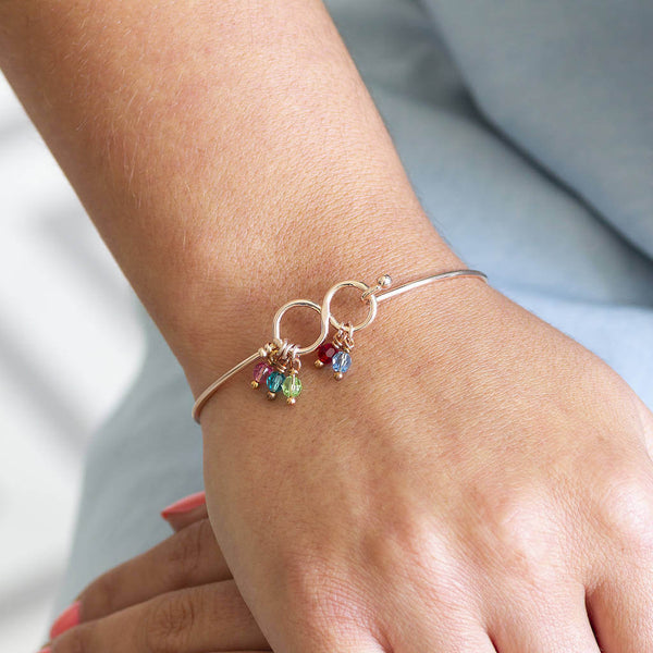 Image shows model wearing family infinity birthstone bangle