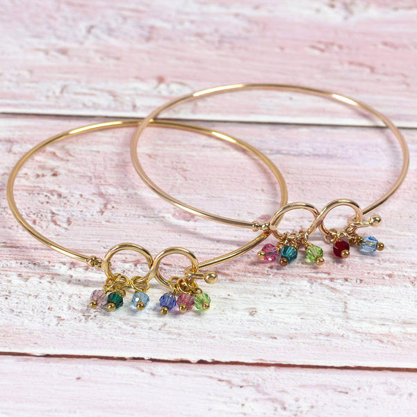 Image shows two gold family infinity birthstone bangle