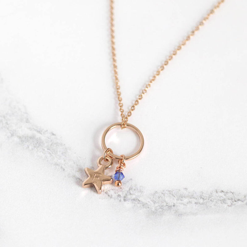 Image shows floating circle necklace with personalised star charm with the initial E and September birthstone