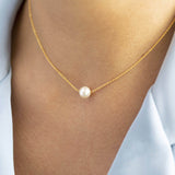 Model wears gold floating pearl necklace with ivory pearl