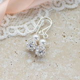Glitterball and pearl earrings sitting on a stone  coaster with white lace and pink ribbon