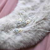 Glitterball and pearl pendant and earring jewellery set lying on a grey fur 