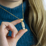 Image shows model holding Gold Feather Enamel Necklace