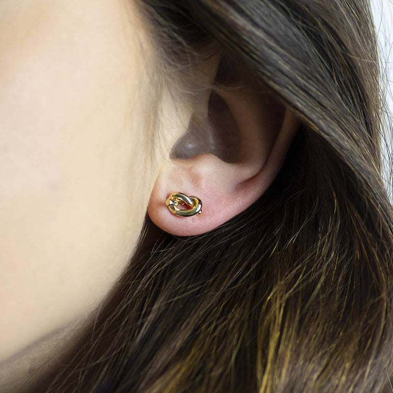 Image shows model wearing gold friendship knot stud earrings